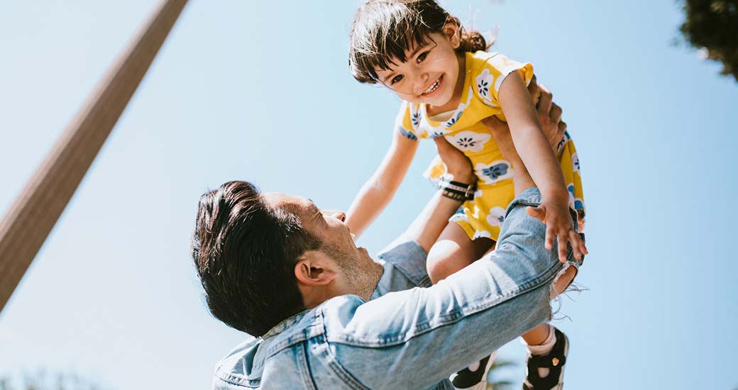father holding up daughter smiling